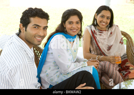 One man and two women sitting in the garden Stock Photo