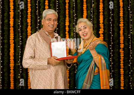 Indian man giving a jewelry to his wife, woman surprised Stock Photo