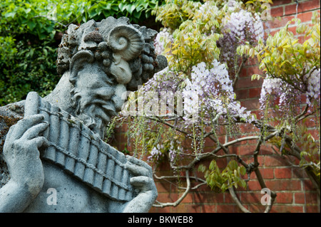 Pan statue with wisteria wall background at RHS Wisley gardens, Surrey, England Stock Photo