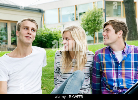 Three students sitting on the lawn Stock Photo