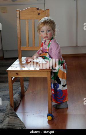 TWO YEAR OLD PLAYING MOTHER: Two year old child baby girl play plays playing with water chair cloth sponge kitchen home Model released Stock Photo