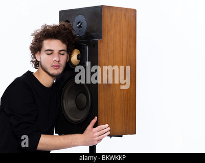 studio portrait of a one caucasian young man listening to music lover with speakerphones isolated on white background Stock Photo