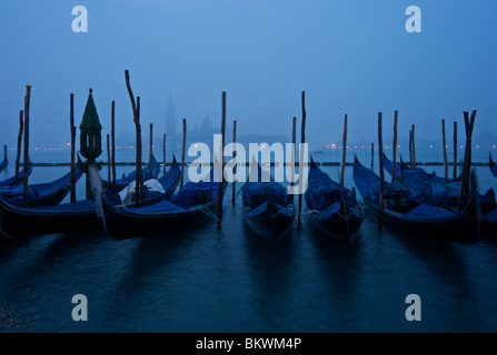 Moored gondolas in the blue light of dawn by the Piazza San Marco facing the Guidecca and Basilica di San Giorgio Maggiore Stock Photo