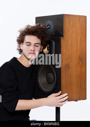 studio portrait of a one caucasian young man listening to music lover with speakerphones isolated on white background Stock Photo