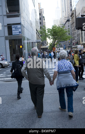 Older couple walks hand in hand down 5th Avenue in New York CIty. Stock Photo
