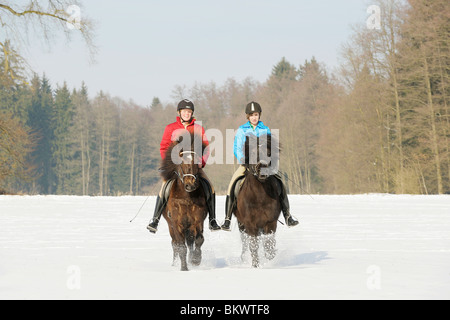 two girls riding on Icelandic horses in snow