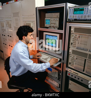 Male engineer using computers to diagnose and repair telecommunications equipment Stock Photo