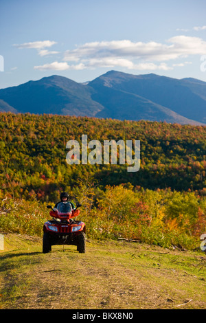 A man rides his ATV on a ridge at Jericho Mountain State Park in Berlin, New Hampshire.   Presidential Range in the distance Stock Photo