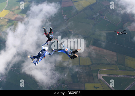 Three skydivers in free fall with a fourth one below them