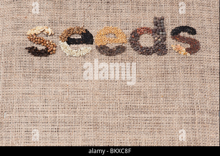 The word 'seeds' spelt out with vegetable and flower seeds on hessian Stock Photo