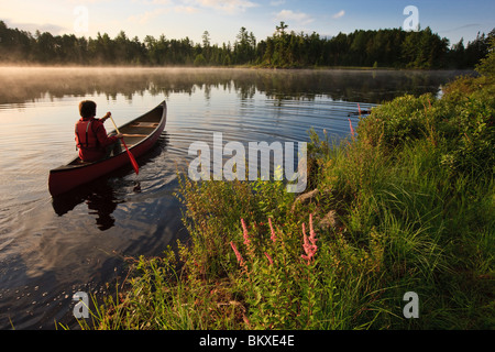 A man canoeing on Little Bear Brook Pond in Errol, New Hampshire. Northern Forest Stock Photo