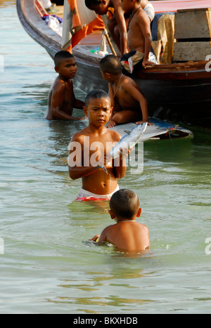 young boy with fresh fish in the sea ,chao leh, sea gypsy village , rawai beach , phuket island ,thailand Stock Photo