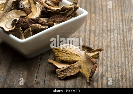 Dried Porcini Mushrooms In A White Dish On A Rustic Kitchen Table Stock Photo