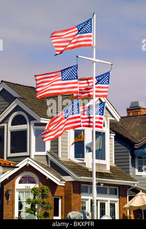Five red, white and blue U.S. flags wave in the breeze from a flagpole in front of a home on Balboa Island in Newport Beach, Southern California, USA. Stock Photo