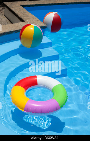 Inflatable rubber ring and beach balls floating in a blue swimming pool Stock Photo
