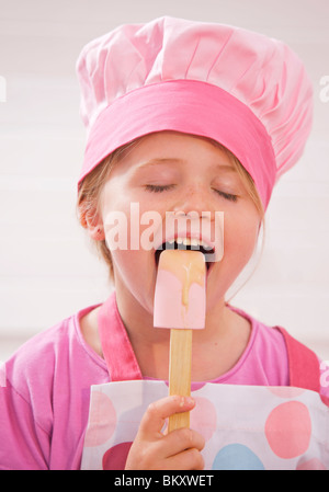 Close up of a young girl licking cake mix from a spatula