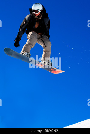 Man in midair jumping while snowboarding Stock Photo