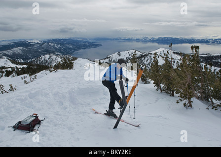 A young man takes his skins off his skis after skinning up a mountain high above Lake Tahoe, Nevada. Stock Photo