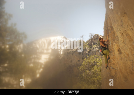 A rock climber ascends a red rock face in Nevada. Stock Photo