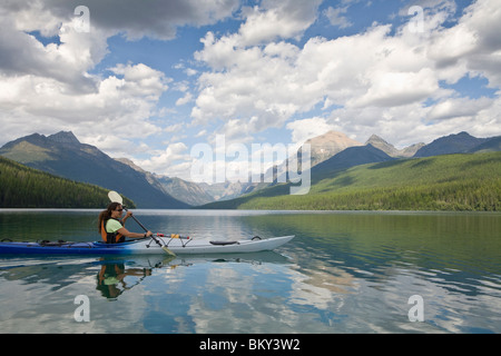 Solo paddler sea kayaking on a remote lake in Glacier National Park. Stock Photo