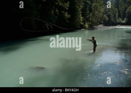 man wearing waders and fishing clothes examines edge of lakebed for flies  before going flyfishing Stock Photo - Alamy