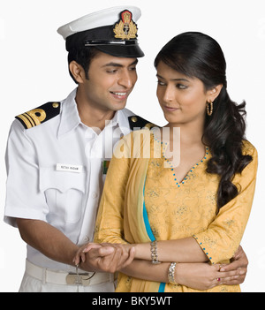 Navy officer embracing a woman from behind Stock Photo