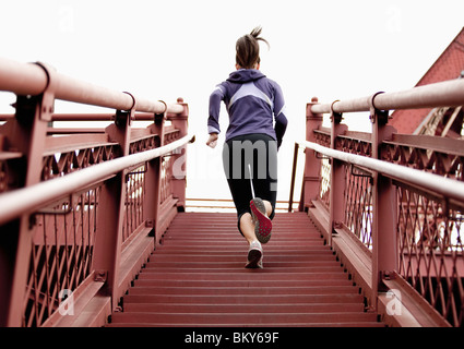 An athletic female in a purple jacket running stairs in Portland, Oregon.