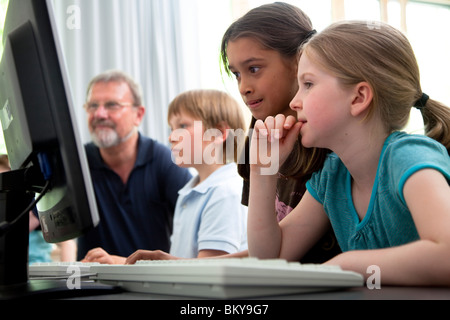Male teacher helping pupils in computer room, Hamburg, Germany Stock Photo