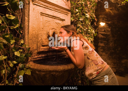Woman at wine fountain in Buda Castle Labyrinth, Woman tasting red wine of the wine fountain in Buda Castle Labyrinth, Buda, Bud Stock Photo