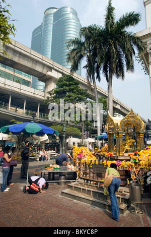 People crouching and praying at Erawan Shrine, Ratchadamri Road near Siam Square, Pathum Wan District, Bangkok, Thailand Stock Photo