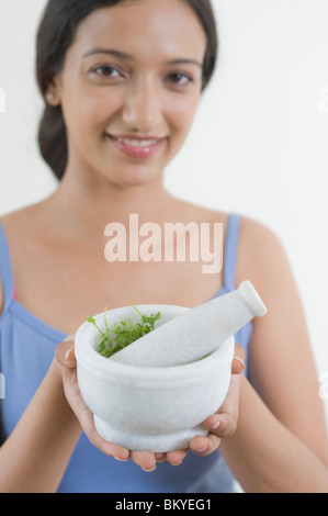 Woman holding a mortar and pestle with cilantro Stock Photo