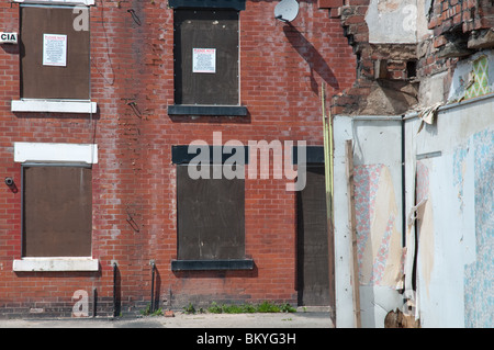 Boarded up terraced houses in East Manchester,England.In the foreground the exposed interior of a partially demolished property. Stock Photo