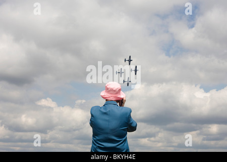 Lady plane spotter watches fly-past of the Blades aerobatic Team at Farnborough 2010 launch. Stock Photo