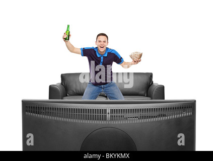 Sport fan with beer bottle and popcorn in his hands watching a match on TV Stock Photo