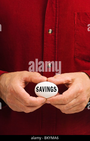 Man holds white egg with Savings written on it, symbolizing the fragility of money matters; the proverbial 'nest egg.' Stock Photo
