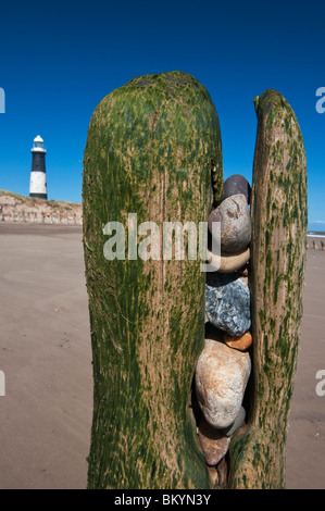Stones trapped in old sea defenses at Spurn Head Nature Reserve near Hull, North Yorkshire with Spurn Point lighthouse. The sea is reclaiming the sand. Stock Photo