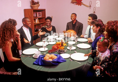 Mixed race group celebrates holiday Thanksgiving dinner meal share laugh love listen tell talk food turkey Stock Photo
