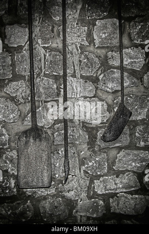 Old tools hanging against a stone wall Stock Photo