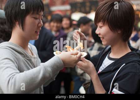 Two young women eating outside the Huxinting Teahouse, Yu Yuan Garden, Nanshi, Feng Shui, Shanghai, China, Asia Stock Photo