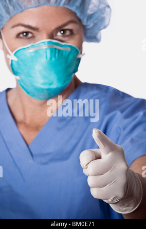 Female surgeon wearing a flu mask and pointing forward Stock Photo