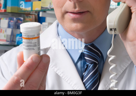 Pharmacist holding a medicine bottle and talking on the telephone Stock Photo