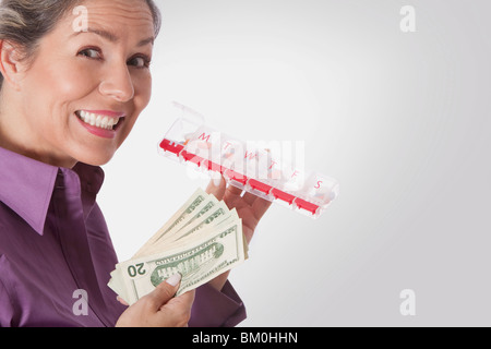 Woman holding pills box and currency notes Stock Photo