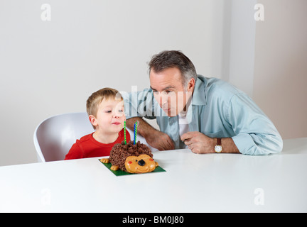 Boy with dad blowing out candles on cake Stock Photo