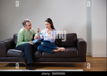 Happy couple opening presents on couch Stock Photo