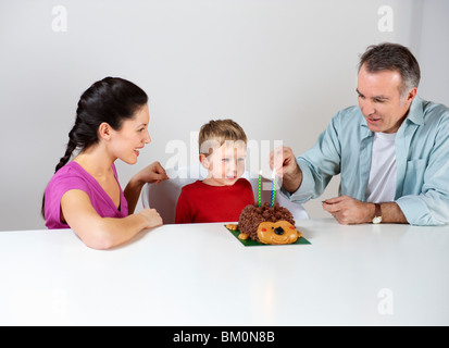 Couple lighting candles on cake for son Stock Photo