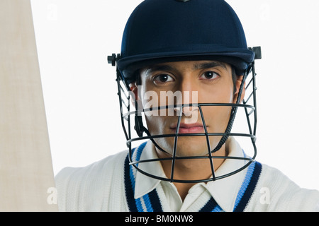 Portrait of a cricket batsman holding a bat Stock Photo