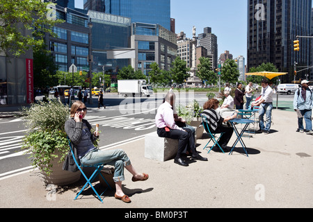 diverse people enjoy outdoor public seating area on Broadway at Columbus Circle on a beautiful  spring day in New York City Stock Photo