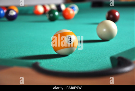 Billiard ball near hole, a lot of balls in blurry background Stock Photo