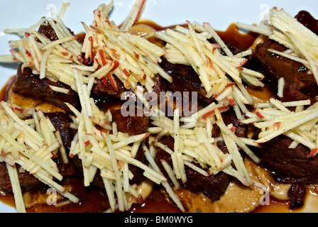 Sharing platter of braised boneless beef short ribs with slivered apple garnish Stock Photo