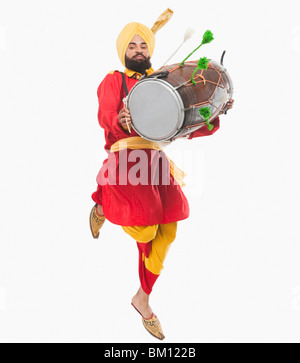 Man performing Bhangra dance with a dholak Stock Photo